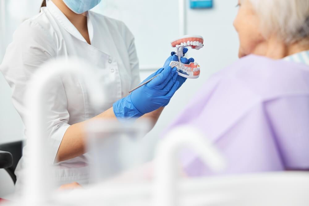 Female medical expert pointing at dental implant in glass tooth
